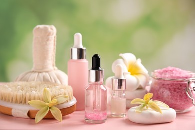 Photo of Composition with spa cosmetic and flowers on pink wooden table