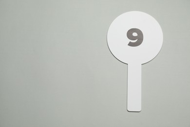 Auction paddle with number 9 on light grey background, top view. Space for text