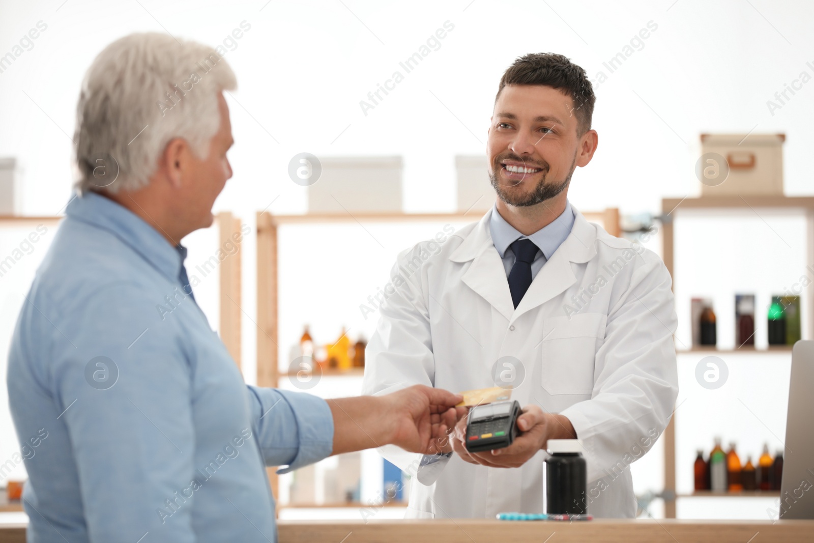 Photo of Customer using terminal for contactless payment with credit card in pharmacy