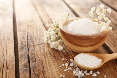 Aromatic sea salt and beautiful flowers on wooden table. Space for text