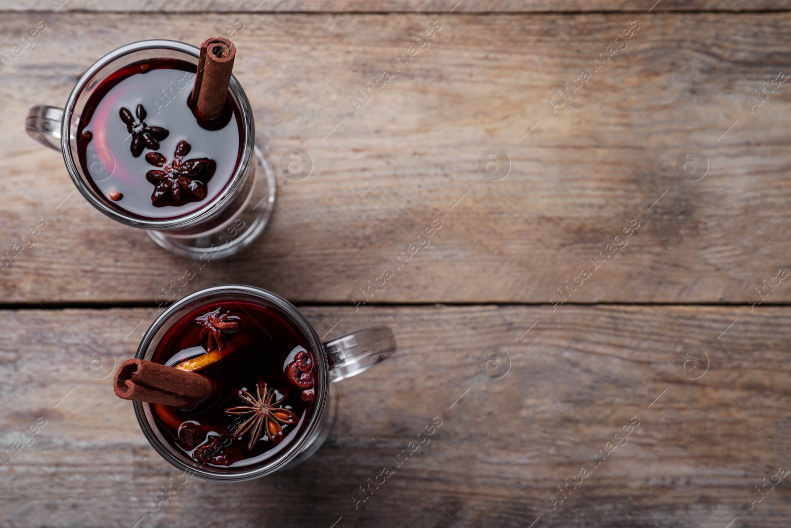 Photo of Delicious red mulled wine on wooden table, flat lay. Space for text