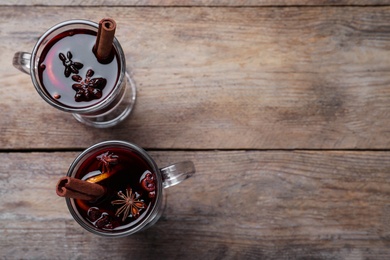 Photo of Delicious red mulled wine on wooden table, flat lay. Space for text