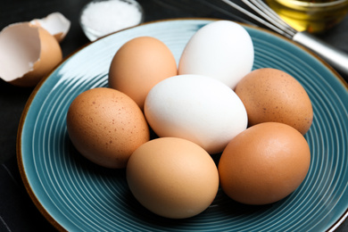 Photo of Different chicken eggs on blue plate, closeup