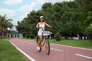 Beautiful young woman riding bicycle on lane outdoors