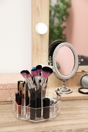 Organizer with cosmetic products for makeup on table near mirror