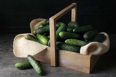 Photo of Wooden basket full of fresh ripe cucumbers on dark grey table