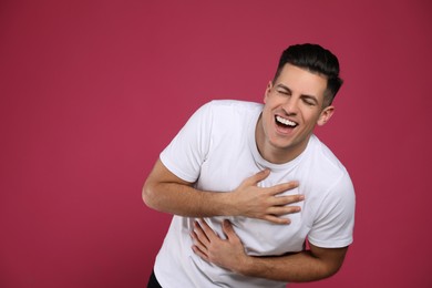 Photo of Handsome man laughing on maroon background. Funny joke