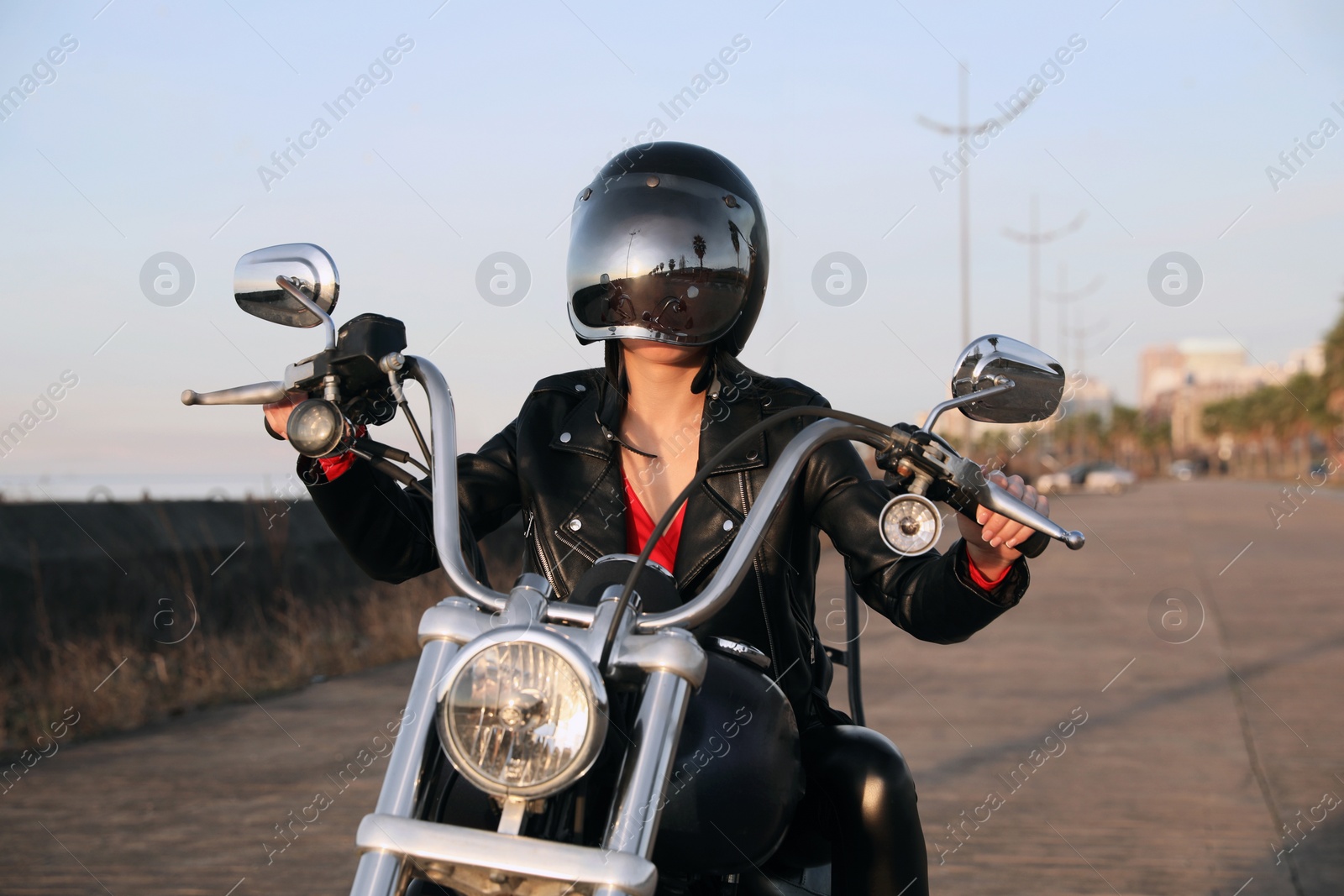 Photo of Woman in helmet riding motorcycle on sunny day