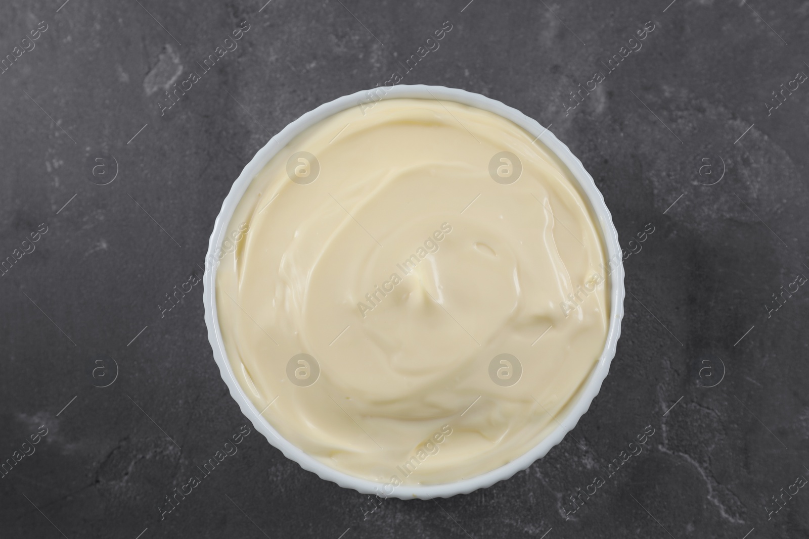 Photo of Fresh mayonnaise sauce in bowl on grey table, top view