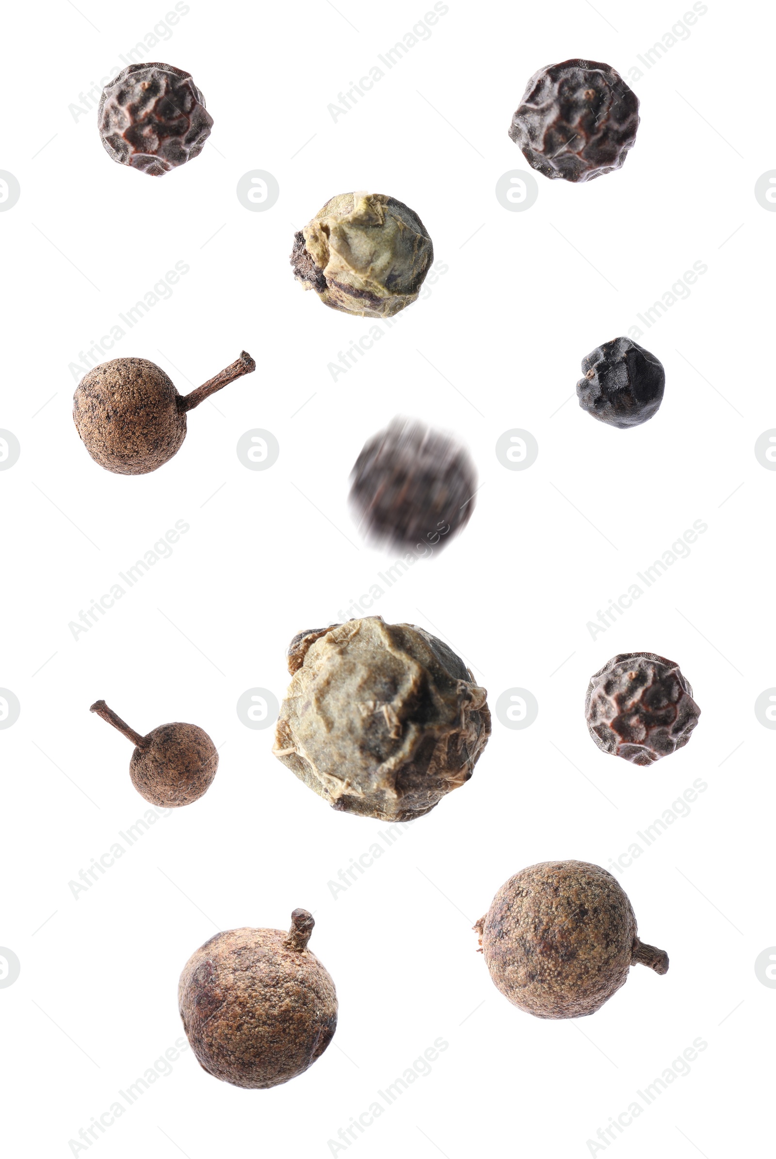 Image of Many different peppercorns falling on white background