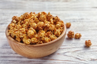 Delicious popcorn with caramel in bowl on table