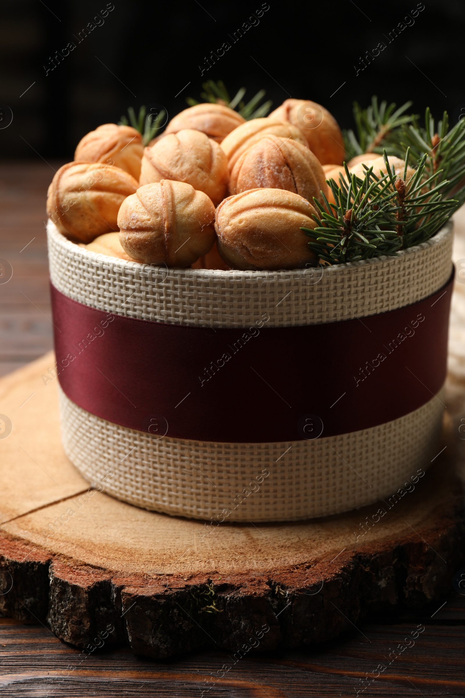 Photo of Bowl of delicious nut shaped cookies and fir tree branches on wooden table