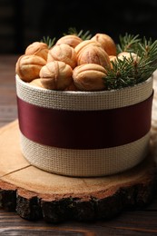 Bowl of delicious nut shaped cookies and fir tree branches on wooden table