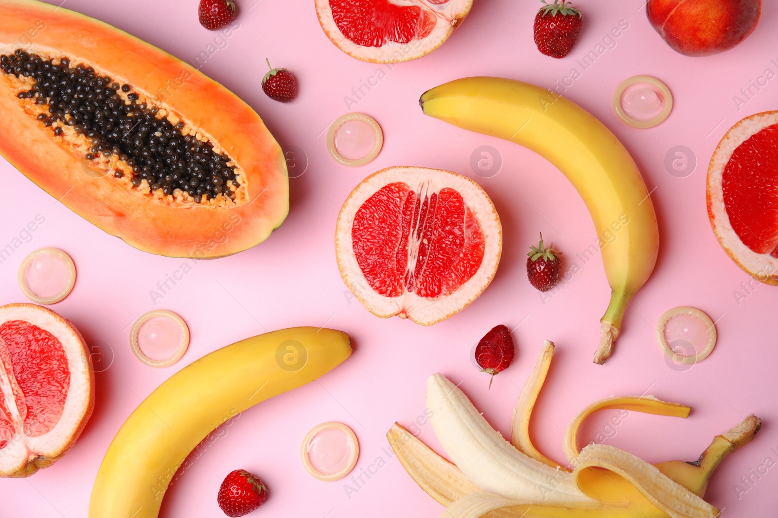 Photo of Flat lay composition with condoms and exotic fruits on pink background. Erotic concept