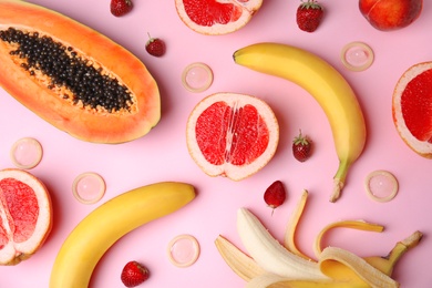 Photo of Flat lay composition with condoms and exotic fruits on pink background. Erotic concept