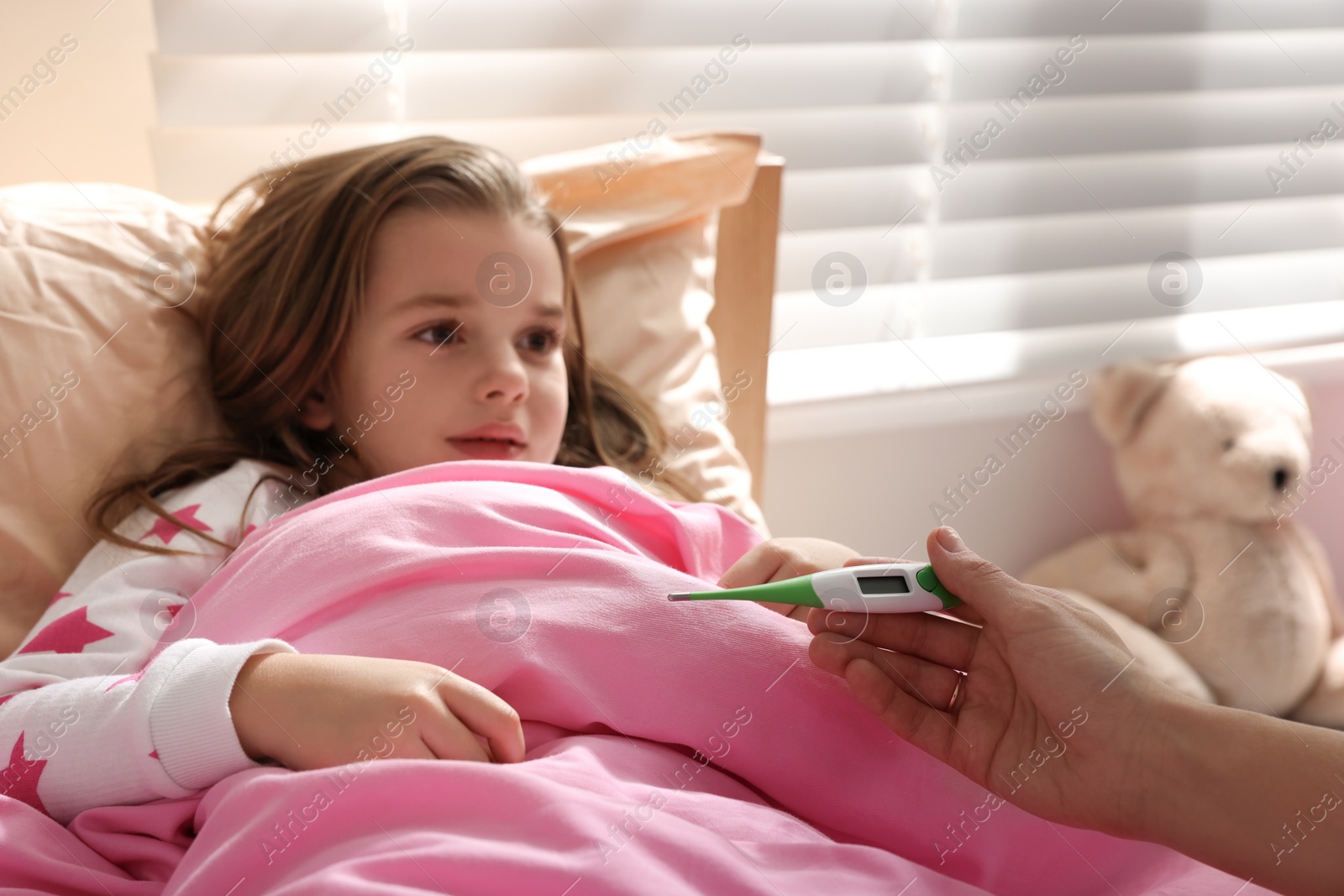 Photo of Doctor with thermometer near little girl in bed indoors