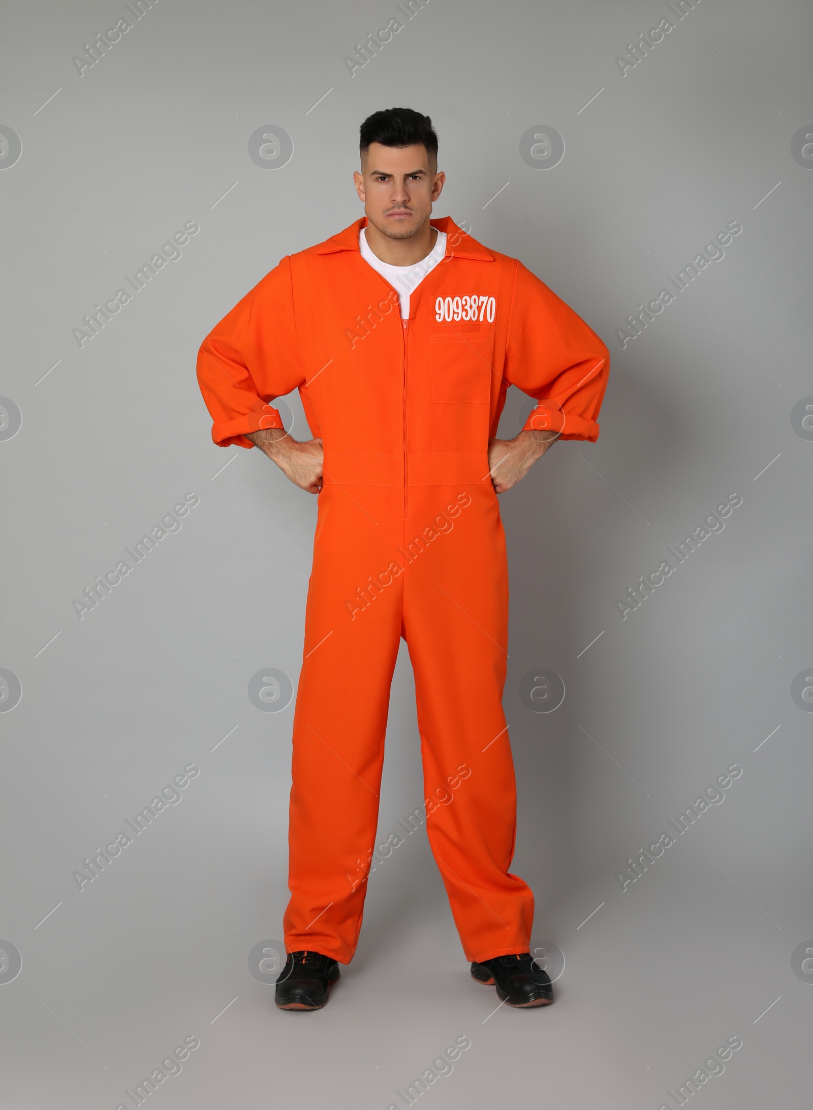 Photo of Prisoner in orange jumpsuit on grey background