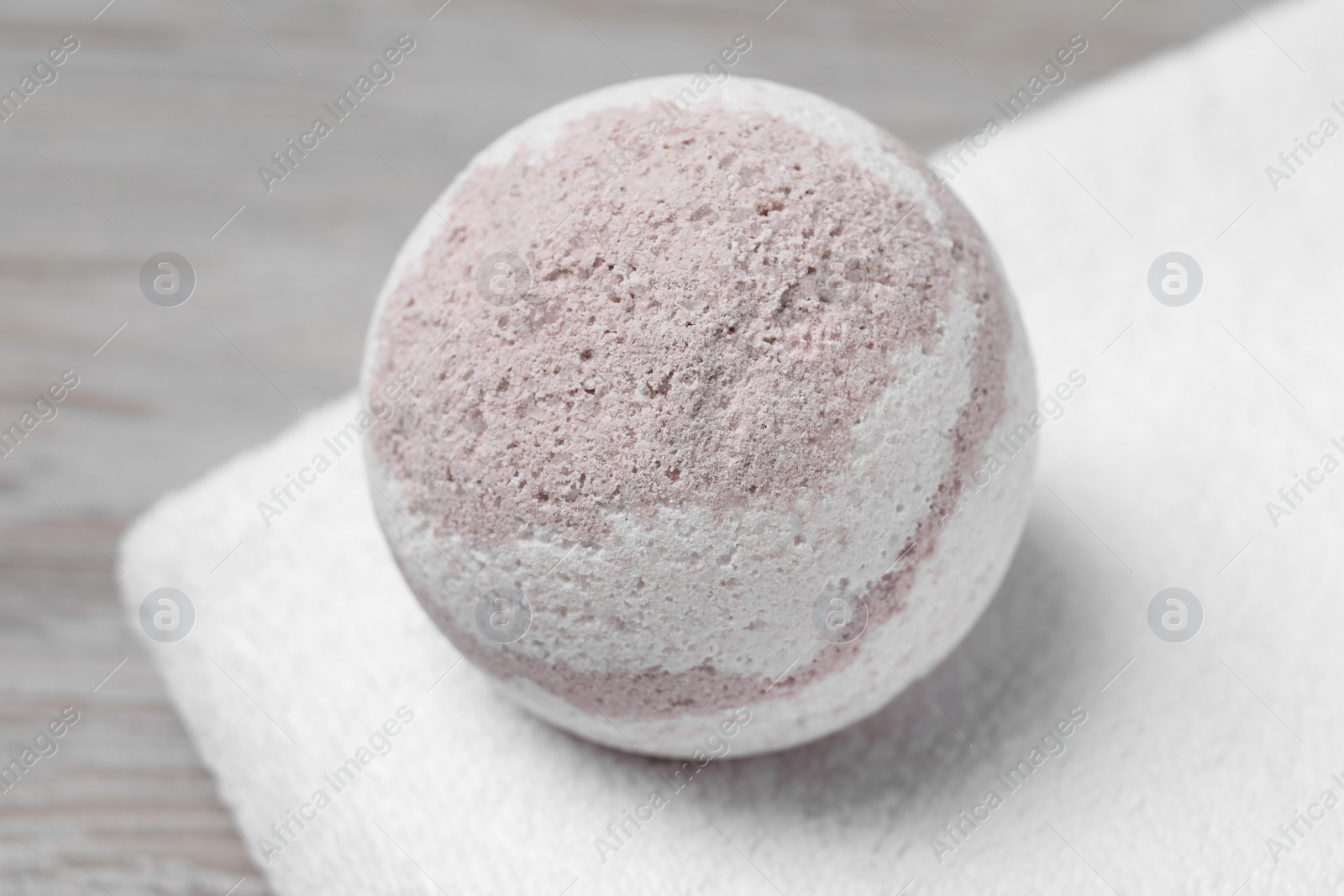 Photo of Bath bomb and towel on table, closeup