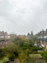 View on city street through window with water droplets on rainy day, closeup