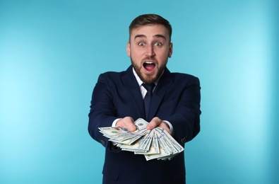 Photo of Portrait of emotional young businessman with money on color background