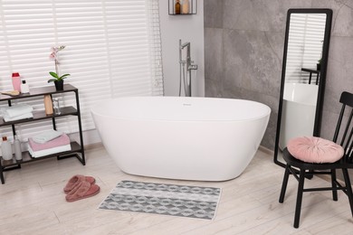 Photo of Stylish bathroom interior with soft bath mat and tub