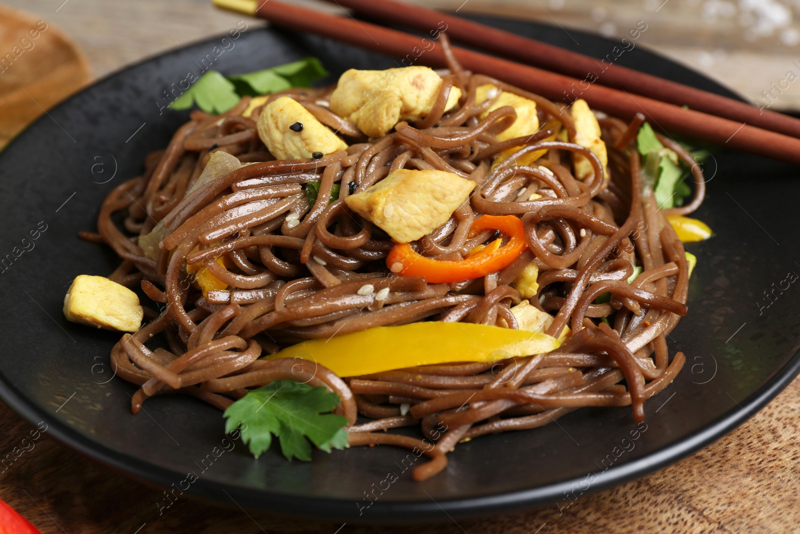 Photo of Stir-fry. Tasty noodles with vegetables, meat and chopsticks on table, closeup