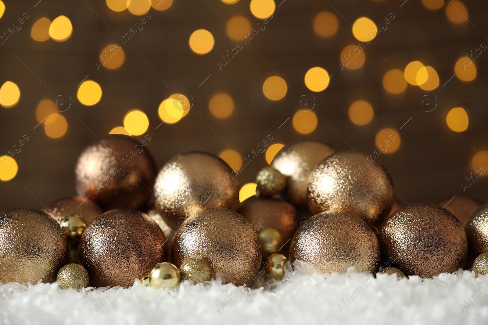 Photo of Beautiful Christmas balls on snow against blurred festive lights. Space for text