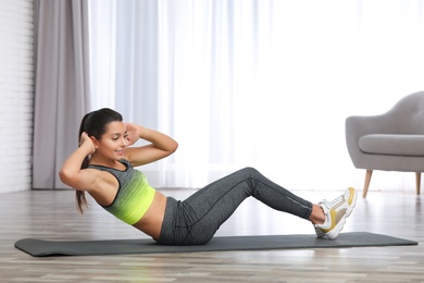 Photo of Young woman in fitness clothes doing exercise at home. Space for text