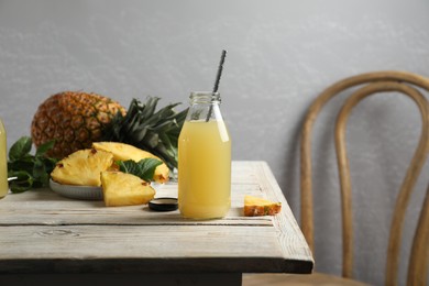 Photo of Delicious pineapple juice and fresh fruit on table indoors