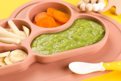 Photo of Healthy baby food. Section plate with delicious broccoli puree, vegetables and fruit on yellow background, closeup