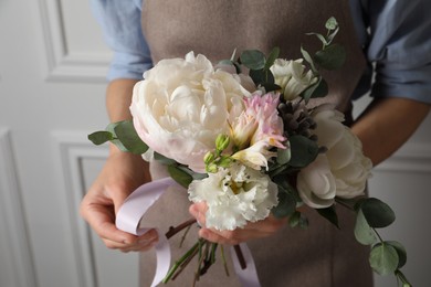 Photo of Florist creating beautiful bouquet at white wall, closeup