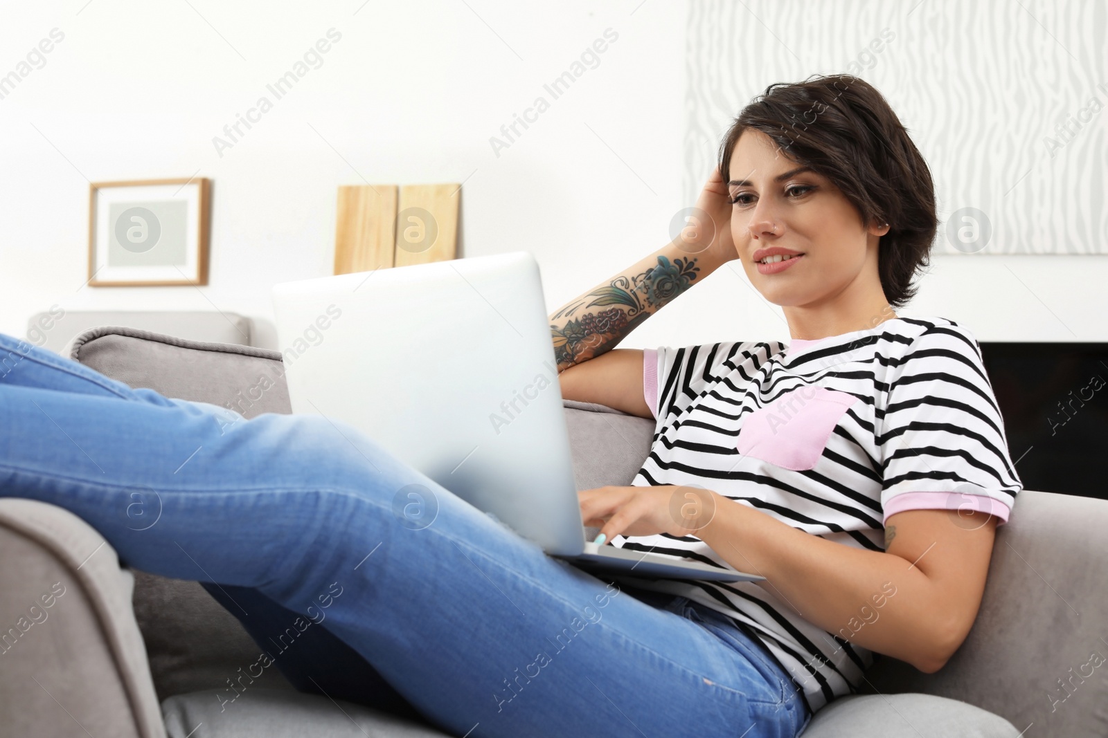 Photo of Young woman with modern laptop sitting in armchair at home