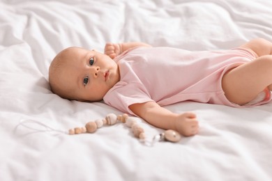Cute little baby with toy lying on white sheets
