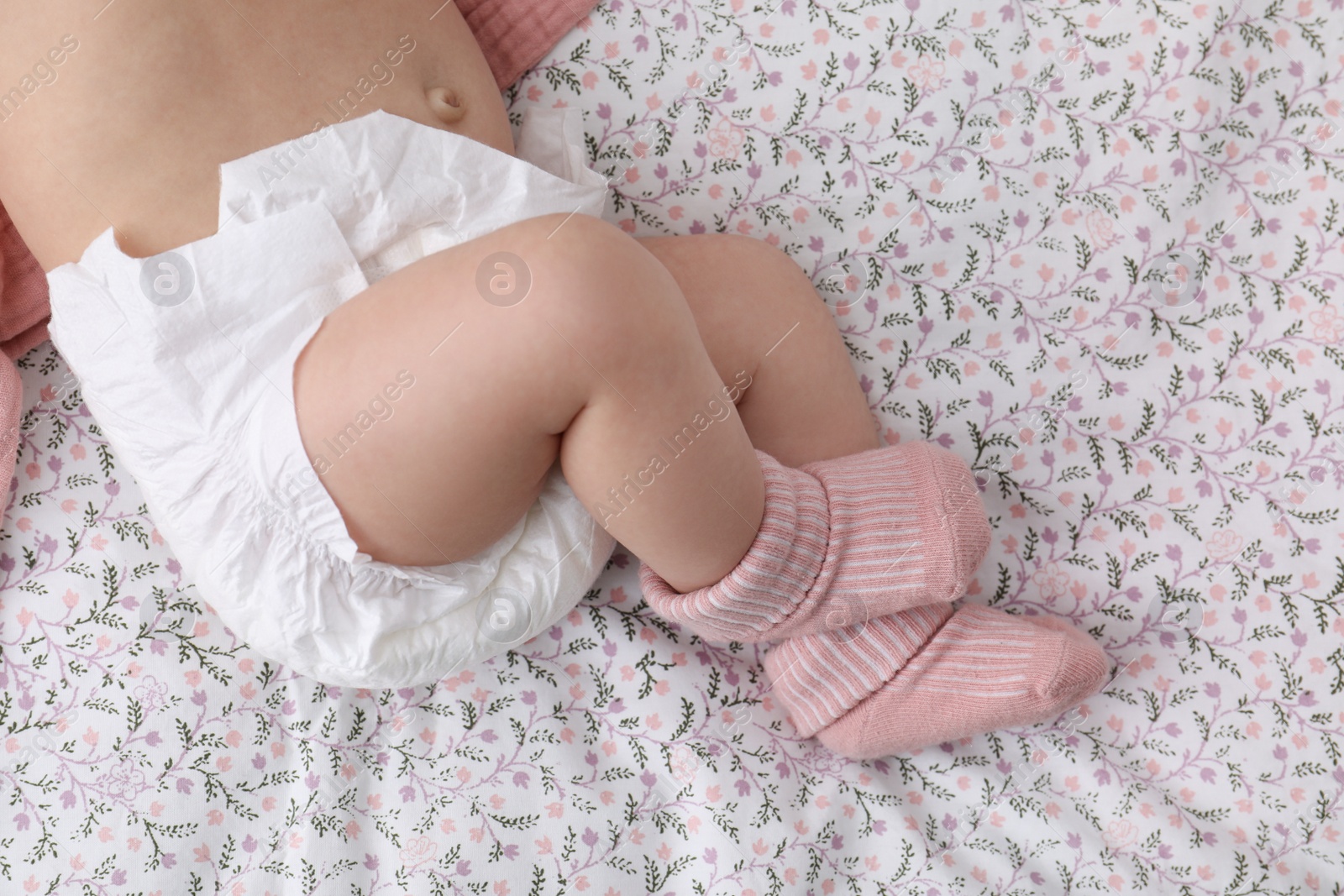 Photo of Little baby in diaper on bed, top view