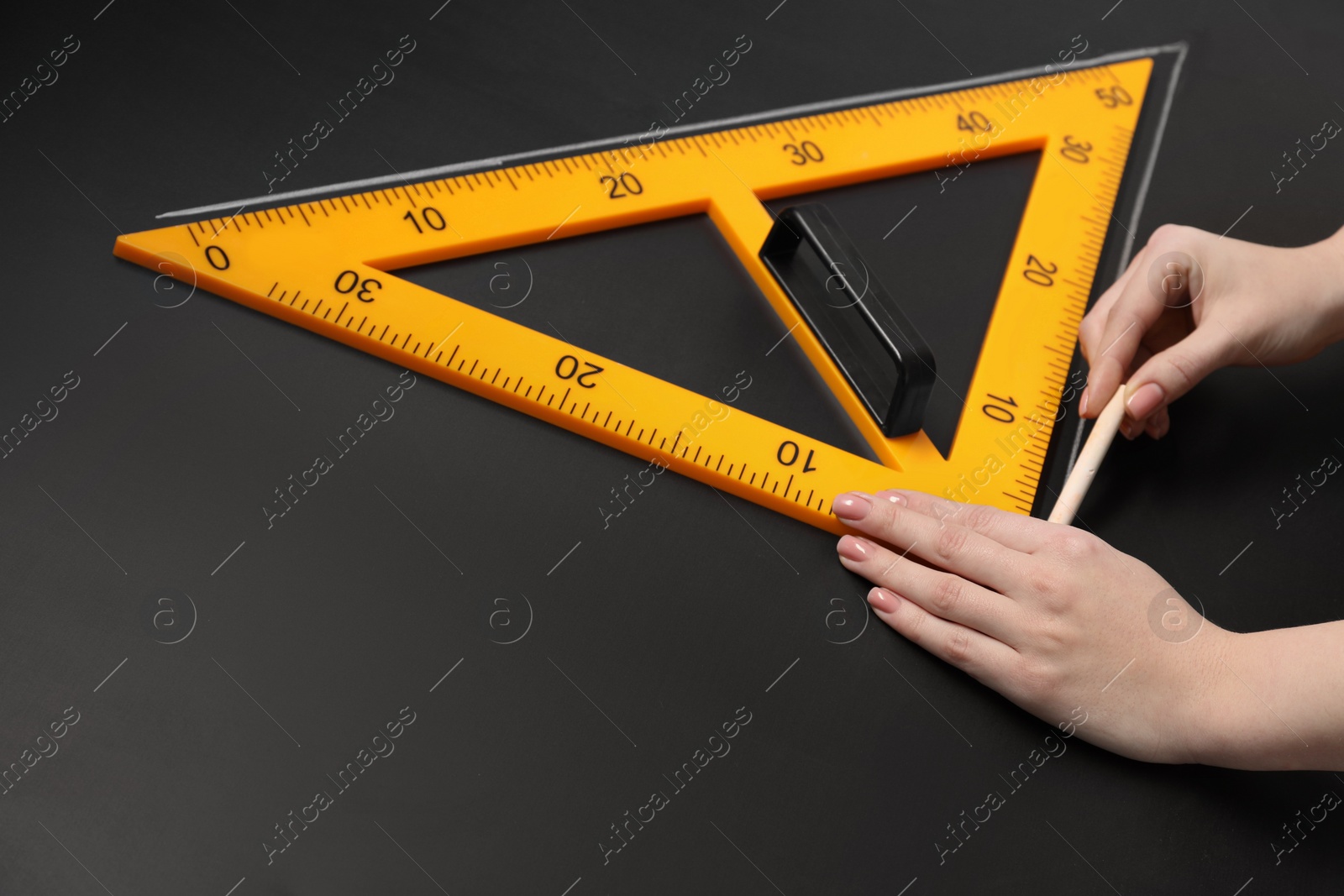 Photo of Woman drawing with chalk and triangle ruler on blackboard, closeup. Space for text