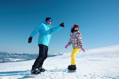 Photo of Couple snowboarding on snowy hill. Winter vacation