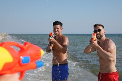 Friends with water guns having fun on beach