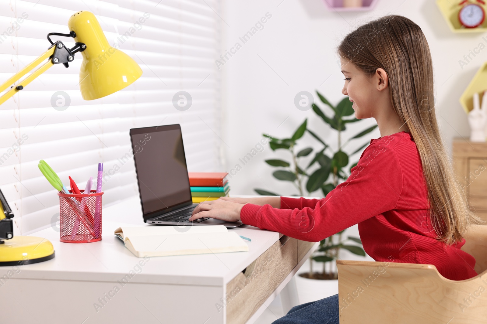 Photo of E-learning. Girl using laptop during online lesson at table indoors