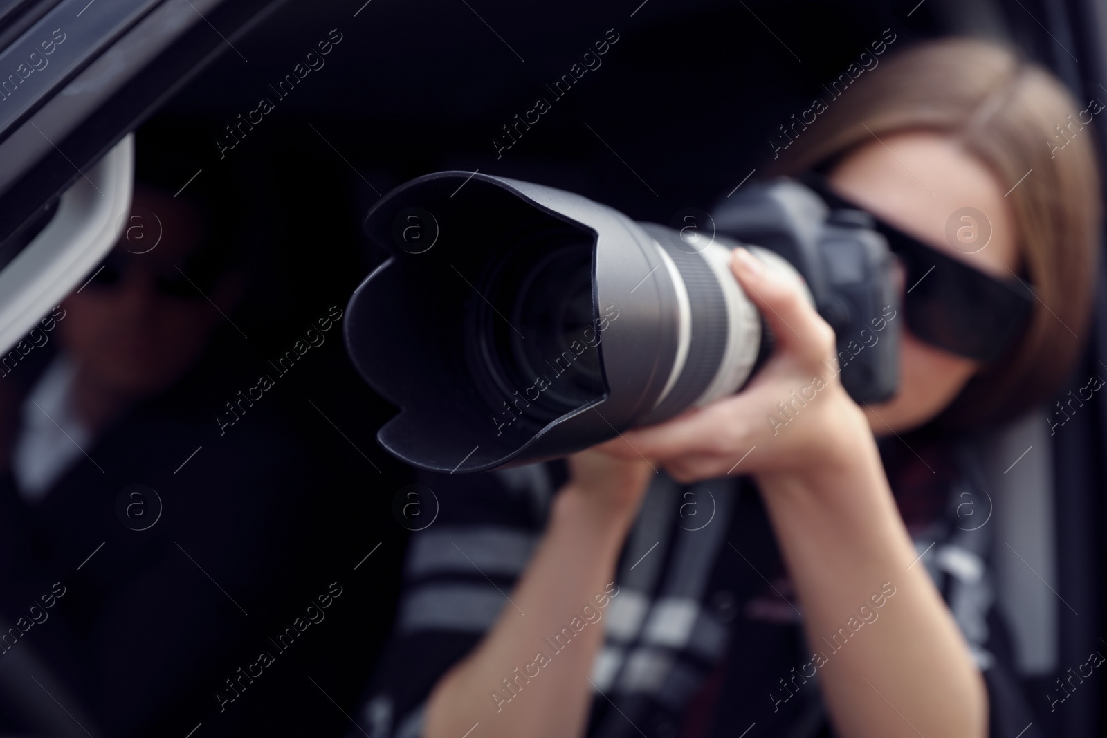 Photo of Private detective with camera spying from car, focus on lens