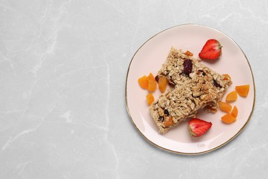 Photo of Tasty granola bars and ingredients on light grey marble table, top view. Space for text