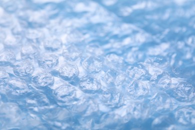 Photo of Transparent bubble wrap on light blue background, closeup