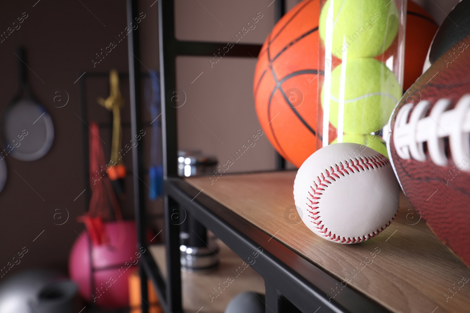 Photo of Different sport balls on shelf in room with other sports equipment