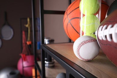 Photo of Different sport balls on shelf in room with other sports equipment