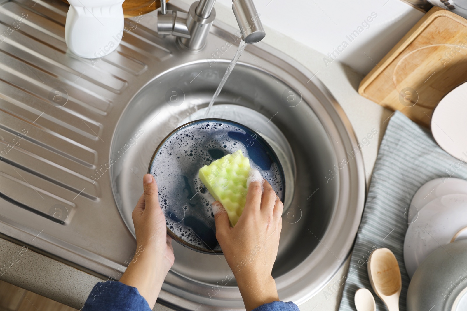 Photo of Woman washing plate in kitchen sink, above view