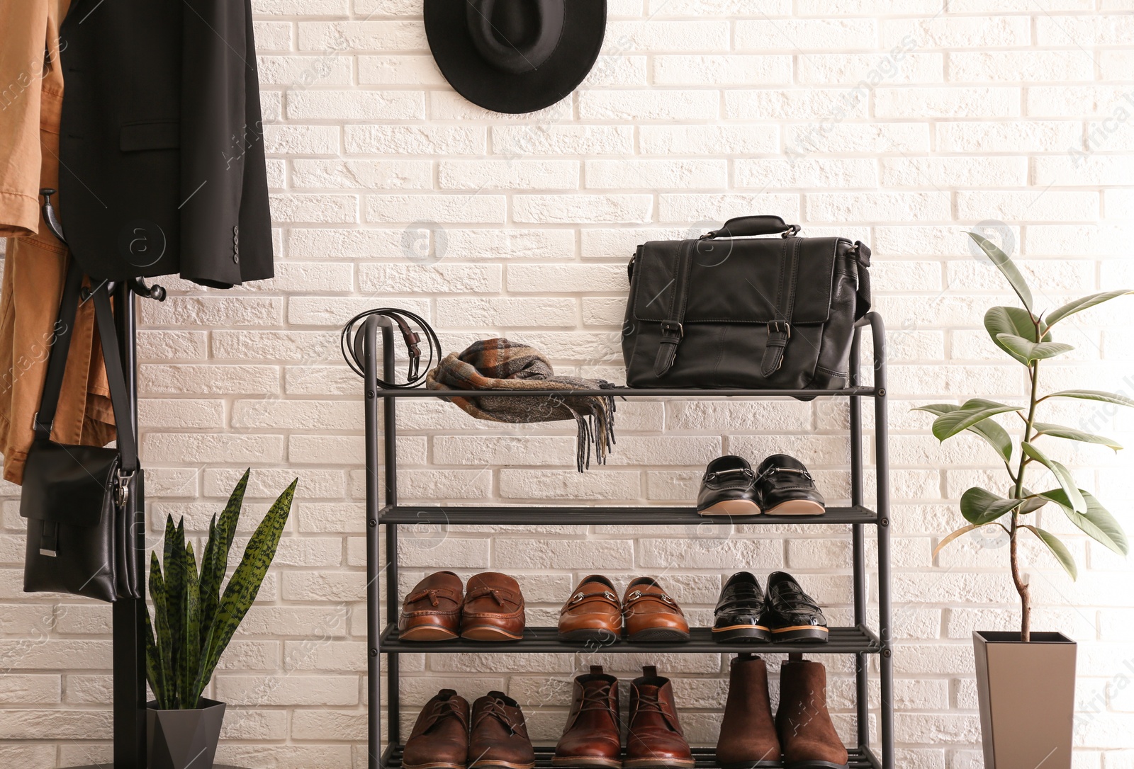 Photo of Shelving rack with stylish shoes and accessories near white brick wall indoors