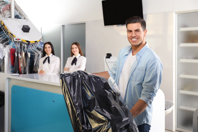 Happy client with clothes at modern dry-cleaner's