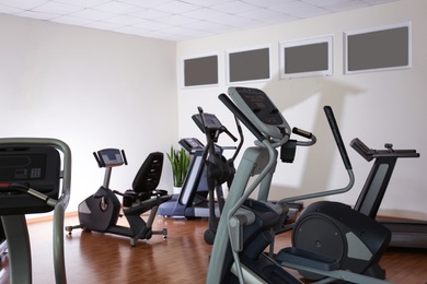 Photo of Elliptical trainers, recumbent bike and treadmill in gym. Modern sport equipment