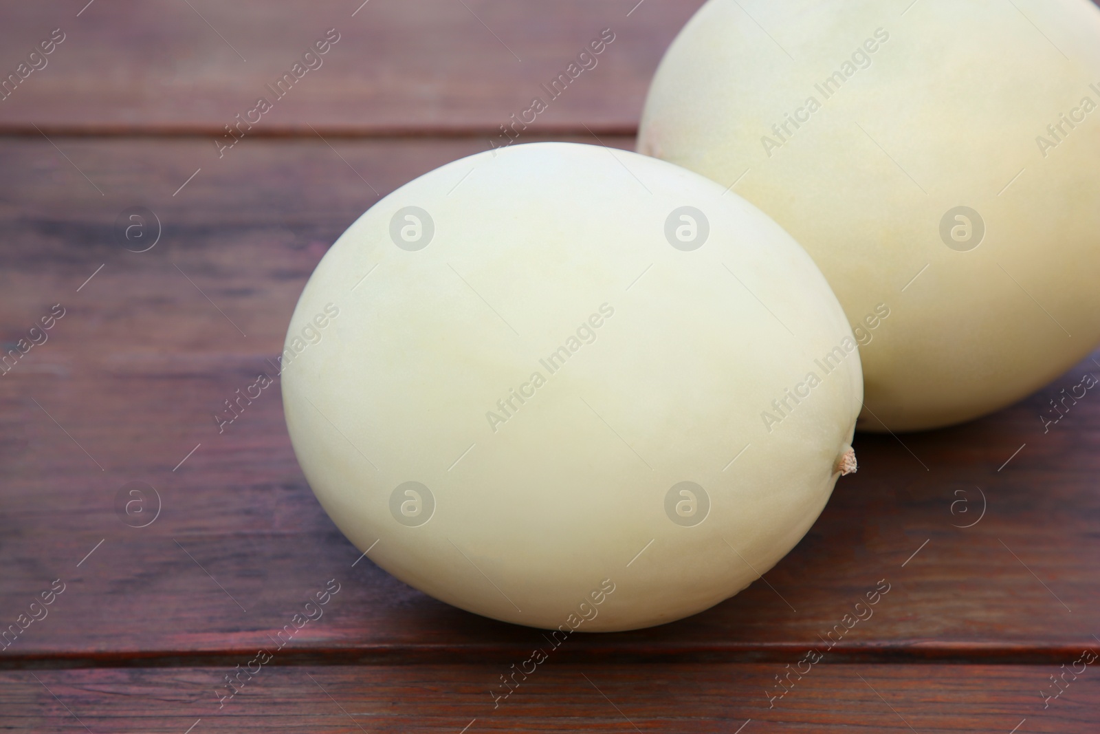 Photo of Whole fresh ripe melons on wooden table, closeup