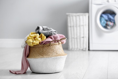 Photo of Wicker basket with dirty laundry on floor indoors, space for text