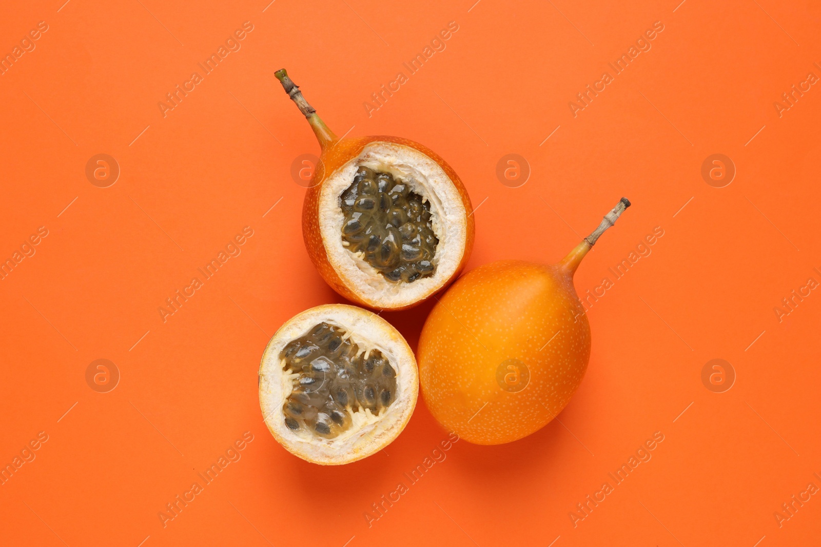 Photo of Delicious ripe granadillas on orange background, flat lay